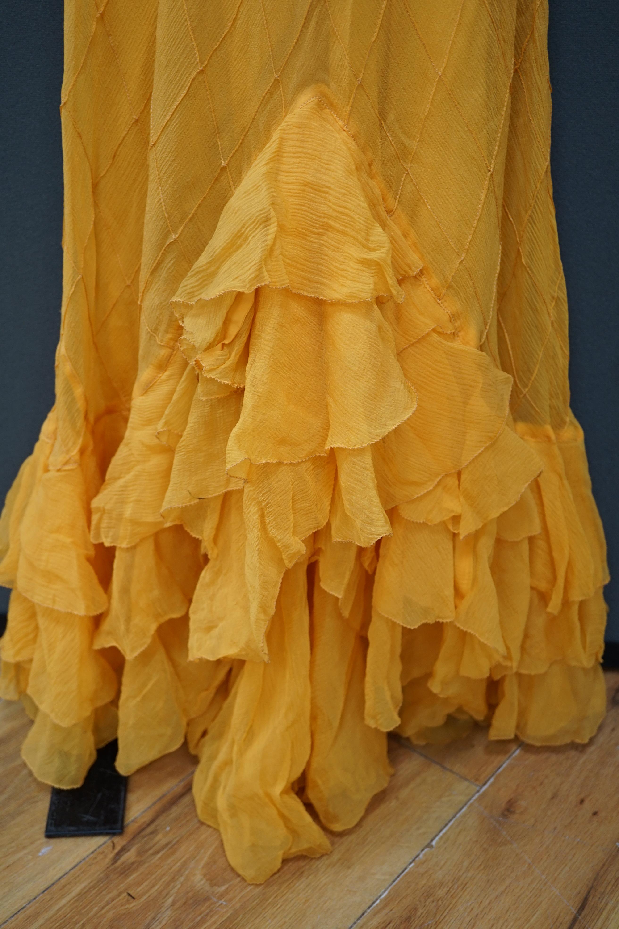 A 1930’s Harrods labelled saffron silk chiffon evening dress and jabot, lined in the same coloured taffeta, the dress kipper shaped with thin camisole straps and the chiffon sewn on the bias in diagonal seams finished wi